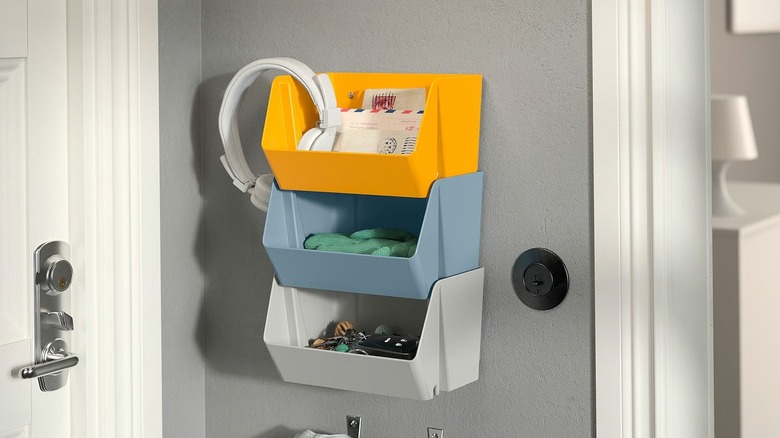 IKEA FODERTRÅG organizers (yellow, blue, and gray) stacked and hung on a wall, holding mail, a headphone and keys
