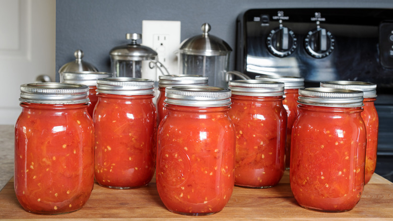 Glass mason jars filled with crushed tomatoes.