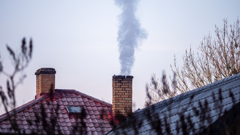 Smoke pours out of an old brick chimney