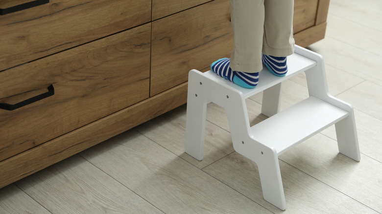 Person using step stool in front of dresser