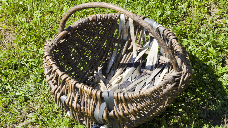 Old wicker basket repaired with tape sitting in grass