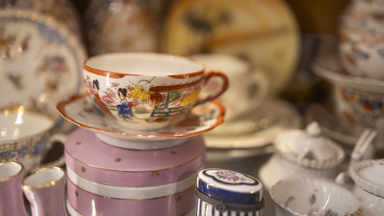 A vintage teacup and saucer stacked on other ceramics