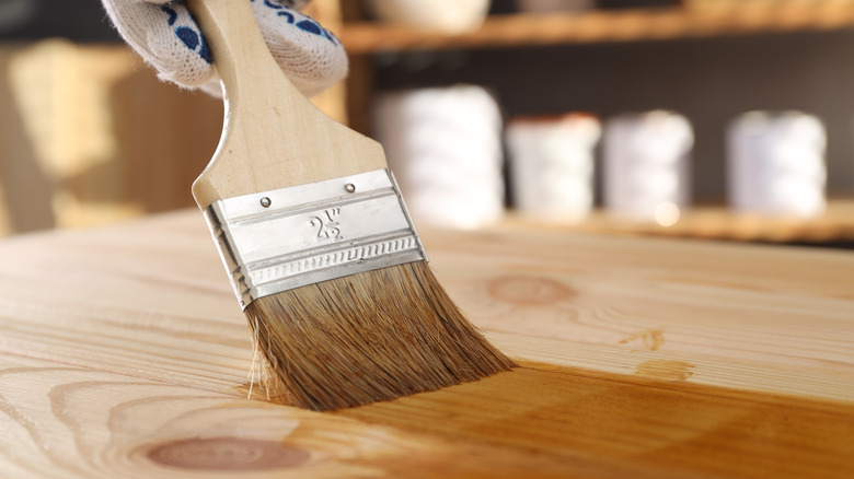 Person using a brush to apply wood stain