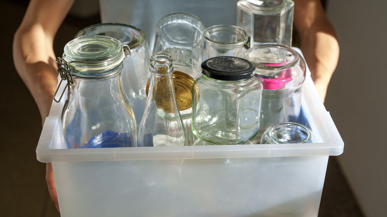 person holding bin of glass containers
