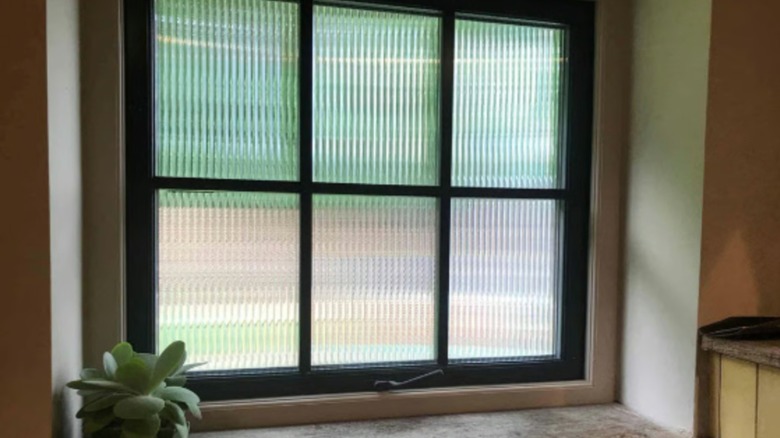 A paneled window is covered in a reeded window film