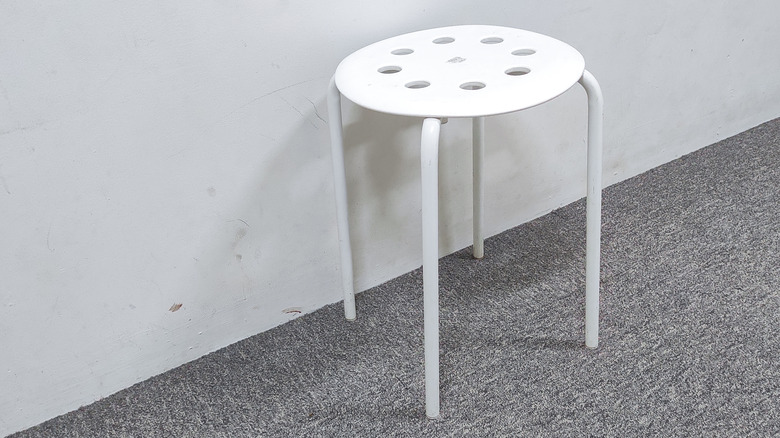 A basic white stool sitting on gray carpet