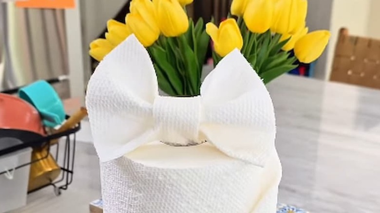 A paper towel roll with DIY bow on top sits on a kitchen countertop.
