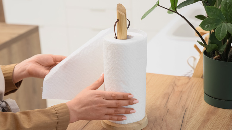 Woman tearing paper towel off paper towel holder.