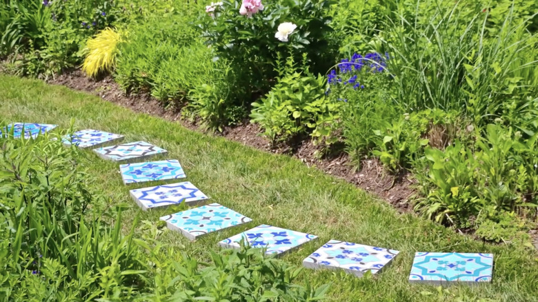 Nine tile patterned stepping stones painted with blue colors in a garden