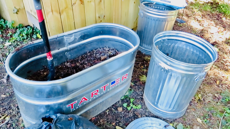 A stock tank and garbage cans are used for leaf-mold creation.