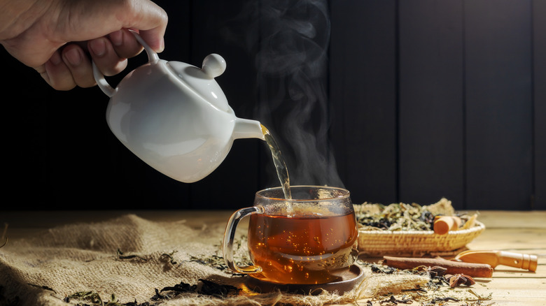 Hand pouring boiling water into herbal tea
