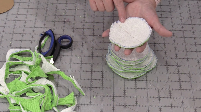 Hand holding makeup remover pads made from old bathroom towels.