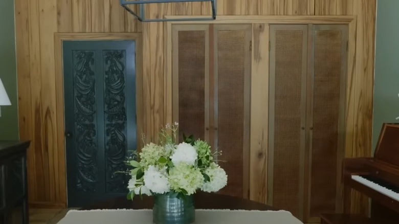 Wood paneled wall with woven cane closet doors