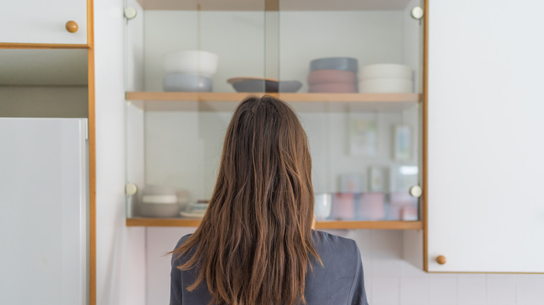 woman open glass kitchen cabinets