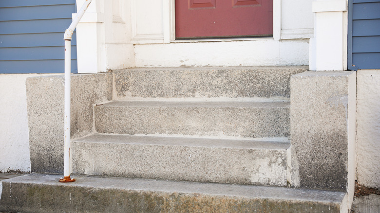 Concrete steps leading up to a red front door.