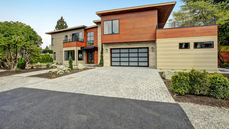 Modern home with driveway made of pavers, asphalt, and gravel