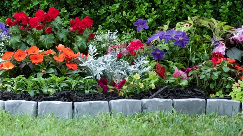 EasyFlex no-dig stone-look edging around a garden bed planted with blooming annuals.