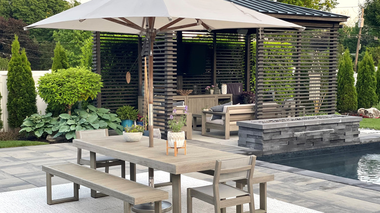 plain white garden umbrella over an outdoor dining table next to a pool