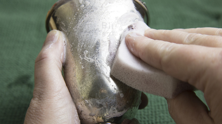 A closeup of someone cleaning a silver cup
