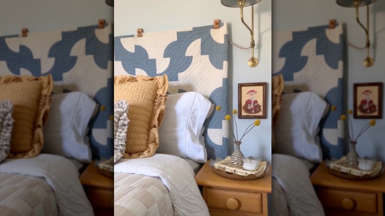 A blue and white quilt hangs behind a bed as a DIY headboard
