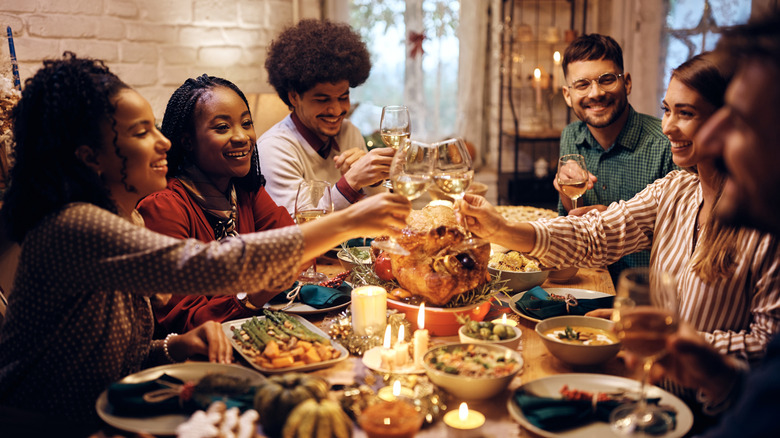 A diverse group of people gather around a table for a holiday meal