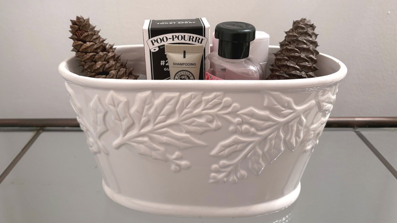 A ceramic dish is filled with travel-sized bath products and scented pinecones