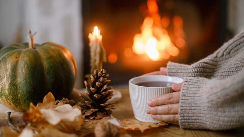 Fall decor with pumpkin and hands holding coffee cup