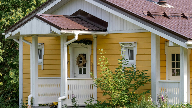 A house with a yellow exterior, and white doors and windows