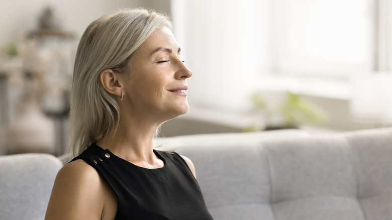 Woman sitting with eyes closed, smelling the room