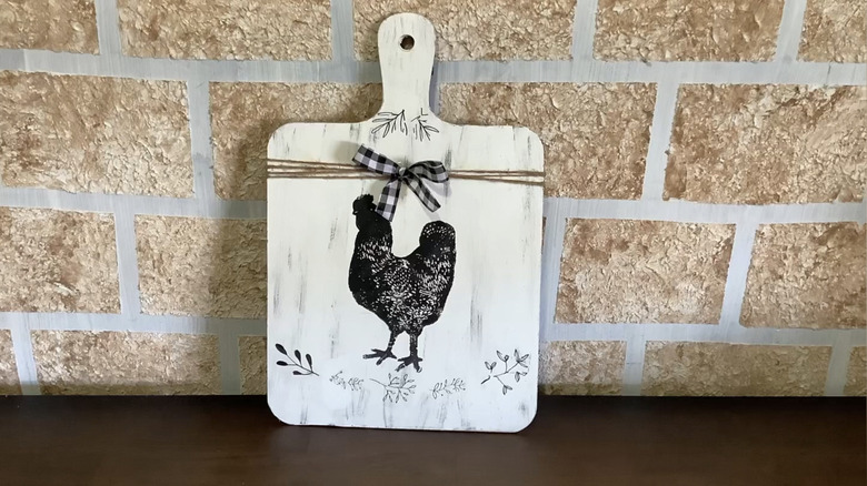 A painted cutting board with a black rooster.