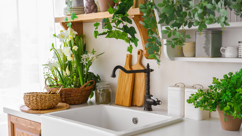 A farmhouse sink with greenery and wood decor.