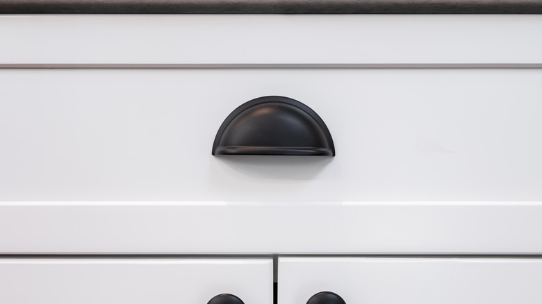 A matte black cup drawer pulls on white cabinets