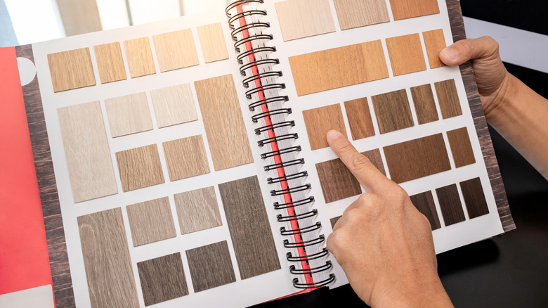 A person points to a square in a book of wooden samples