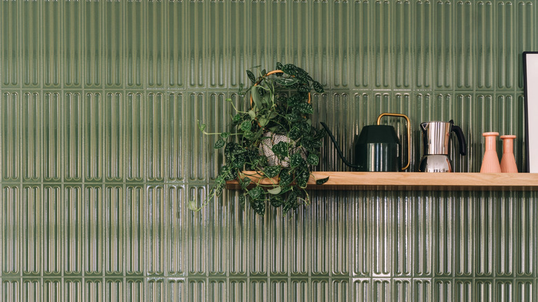Wood open shelf against a dark green tile kitchen backsplash