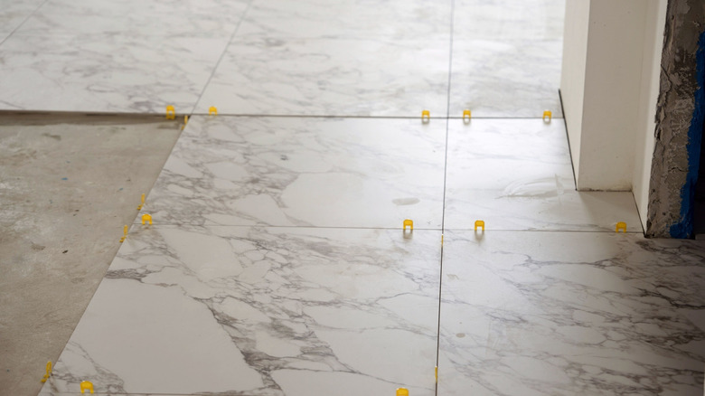 Oversized marble-like tiles being installed in a room