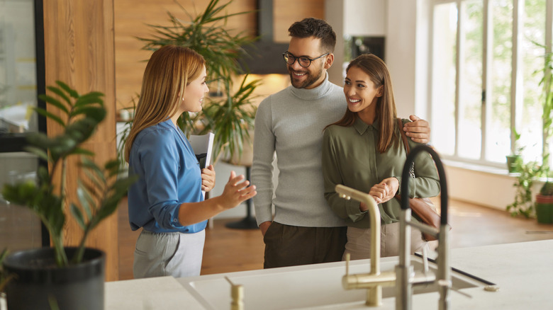 A shop assistant helps a couple in a kitchen showroom
