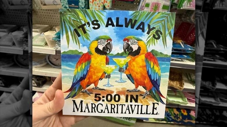 Hand holding a Margaritaville themed decor sign.