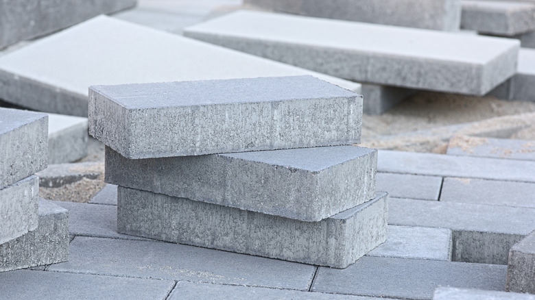 A piles of rectangular cement pavers sits around a walk-way in mid-construction.
