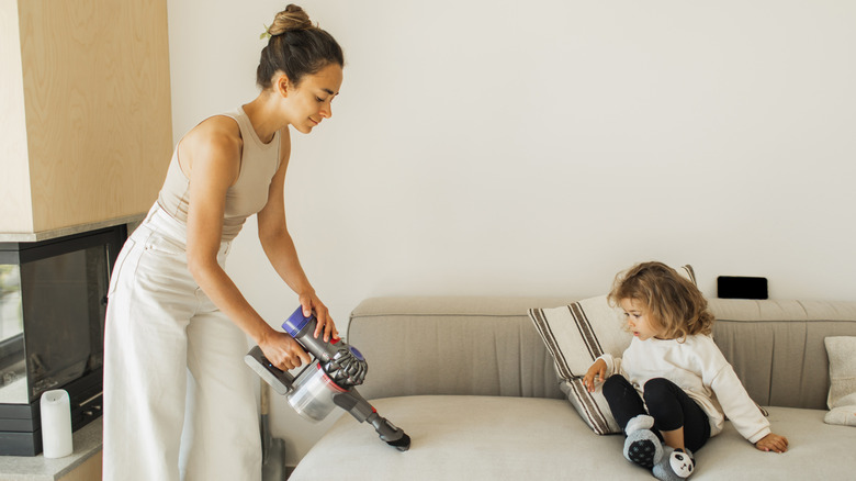 Woman using a handheld vacuum to clean sofa cushions