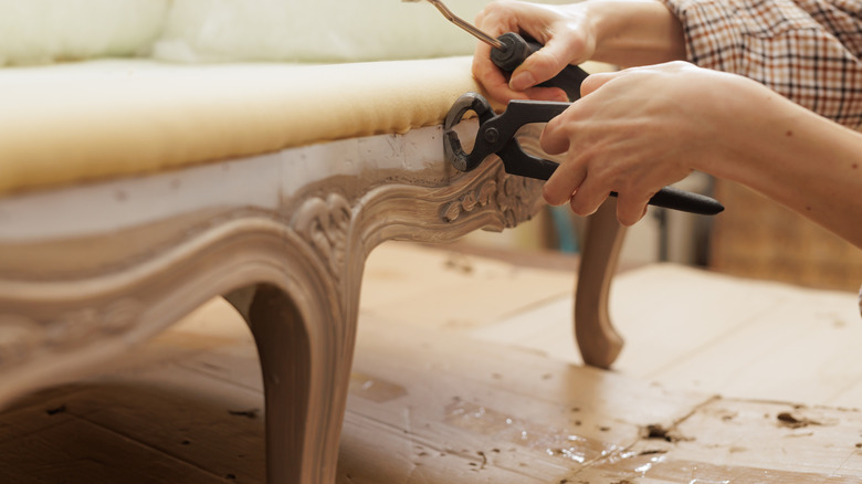 Person reupholstering Victorian furniture piece