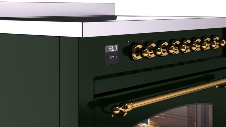 An ivy green range oven with gold hardware and a stainless steel and glass stovetop.