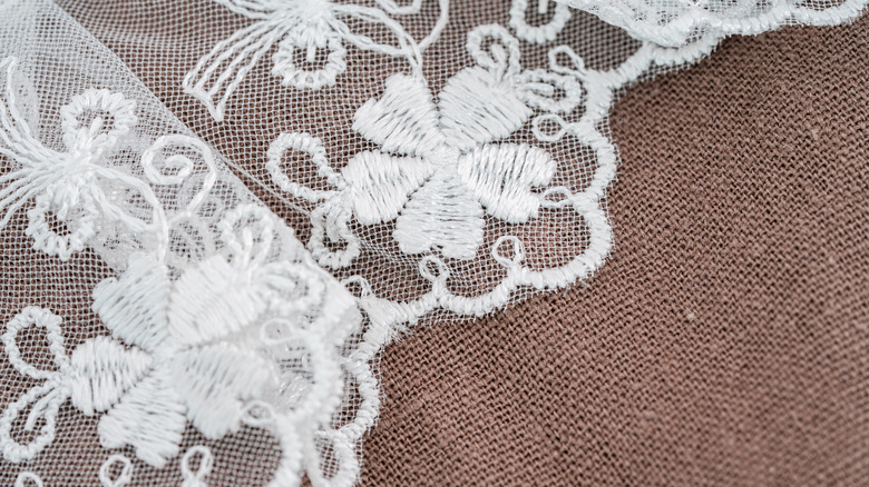 Closeup of white lace curtain overlay on burlap.
