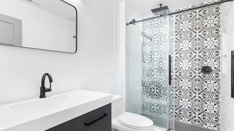 bathroom with black and white mosaic tile on shower wall