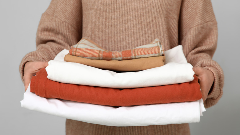 woman holding stack of bed sheets