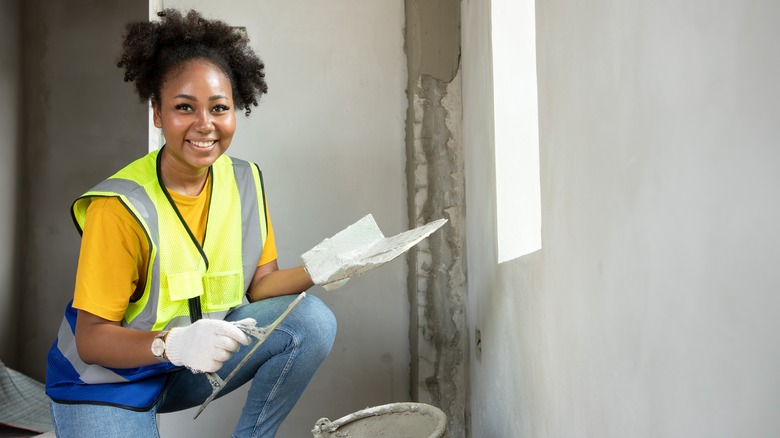 woman plastering walls in home