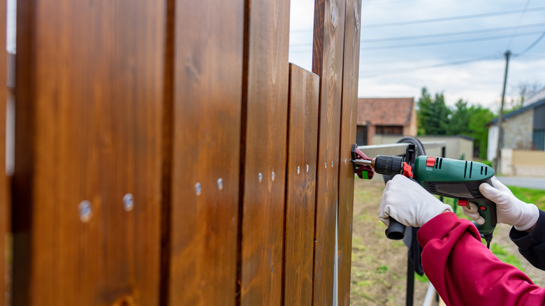 Close up of screw gun being used on wood fence