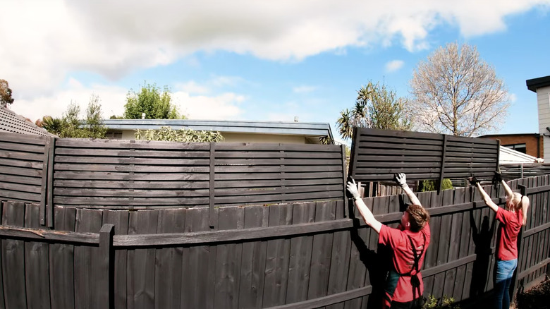 Two people installing fence extension