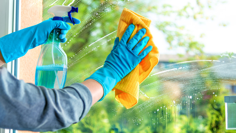 Close up of person using glass cleaner to clean windows