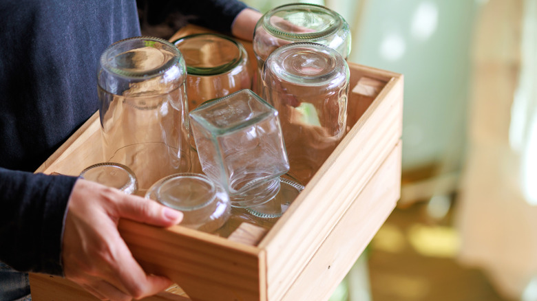 Hands holding a wooden box full of glass jars