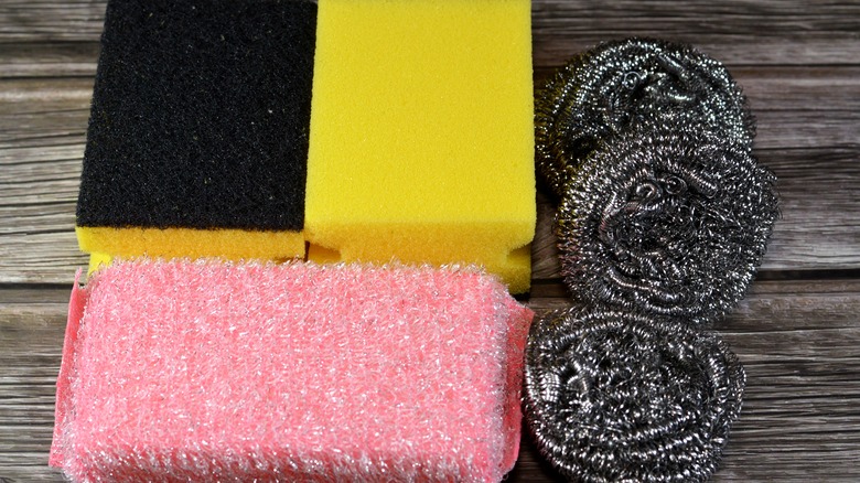 Various abrasive scrubbers on a wooden tabletop.